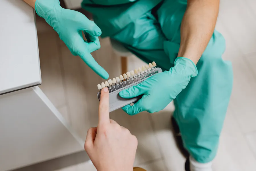 Dental professional pointing at a shade guide for cosmetic dental bonding planning in China - QGO Medical