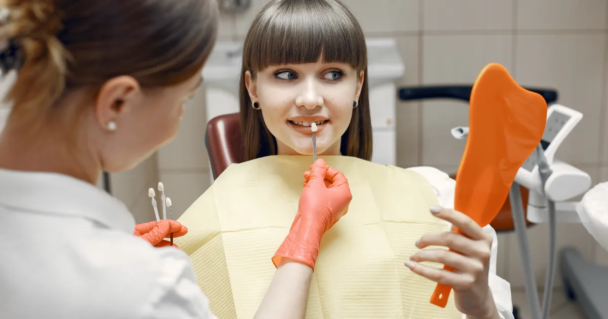 Cosmetic dentist showing veneer shade options for cost of veneers dental planning at a clinic in China - QGO Medical