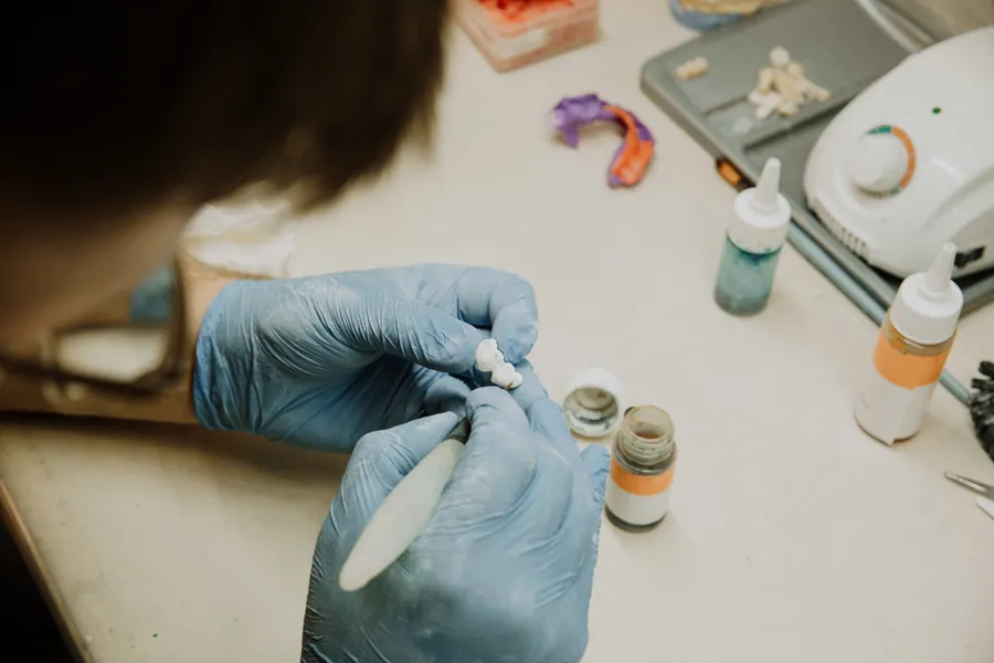 Dental technician shaping a prosthetic tooth for all-on-4 dental implants planning in China - QGO Medical