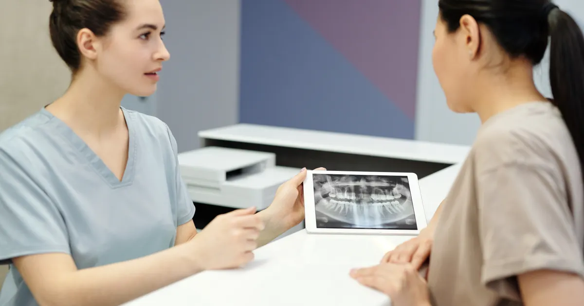 Dentist reviewing dental X-ray for dental veneers for missing teeth planning in China - QGO Medical