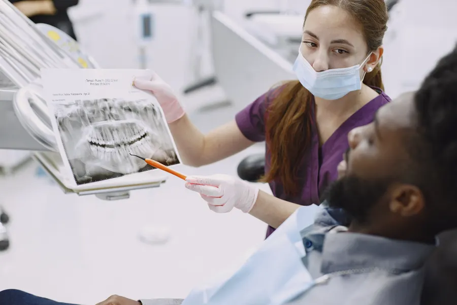 Dentist reviewing dental x-ray before full mouth implant planning in China - QGO Medical