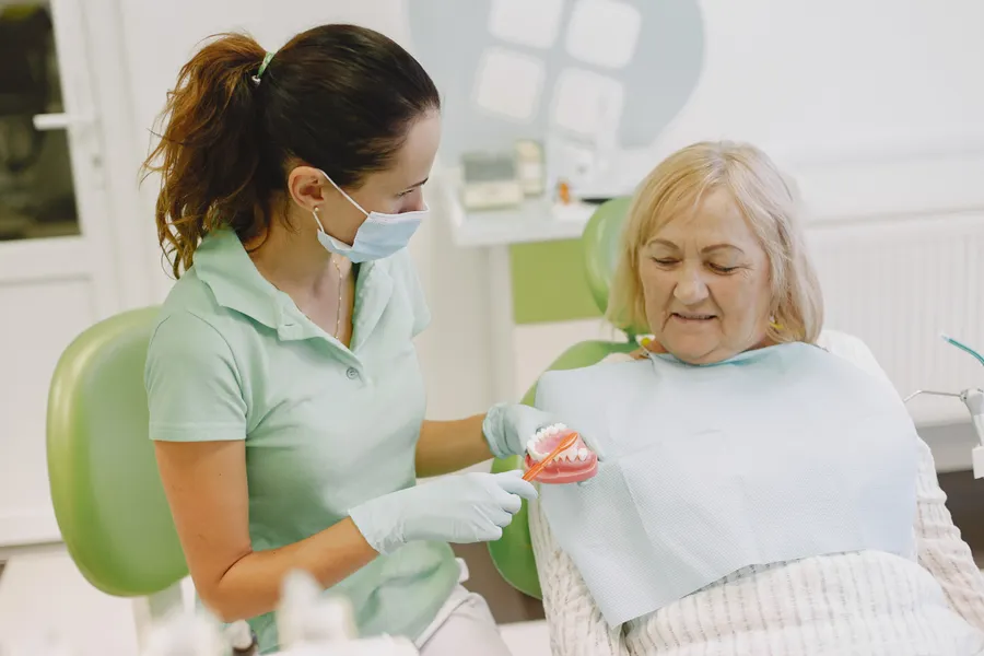 Dentist explaining denture and implant options to older patient in China - QGO Medical