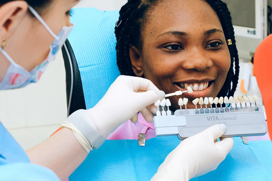 Dentist using a tooth shade guide for veneers and whitening planning in China - QGO Medical